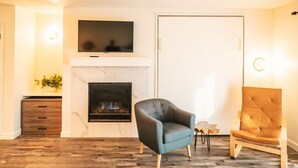 A living room with a fireplace, a television mounted above it, a sofa, and a wooden cabinet. - Riverfront Condo 2 blocks to downtown Bend (Bend)