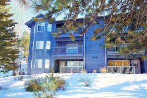 A multi-story building with balconies, a garage, and a snow-covered ground.