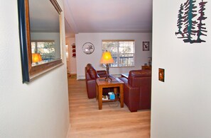 A living room with a wooden coffee table, two leather sofas, a mirror, and a window with blinds.