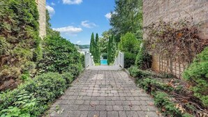 A paved pathway leading to a building with a blue door, surrounded by greenery and trees. - Blackwater Castle w/ Private Pool, Arcade, Hot Tub (Wirtz)
