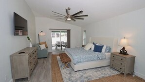 A bedroom with a bed, bedside tables, a ceiling fan, a dresser, and a window. - Discover the perfect vacation rental 3BRD, 2 Bath, heated pool, lanai, parking (Cape Coral)