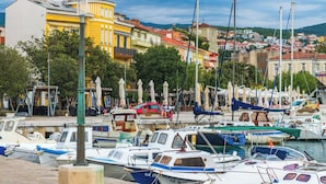 A marina with boats docked, a yellow building, and a town in the background. - Holiday apartment mit Klimaanlage und Terrasse (Crikvenica)