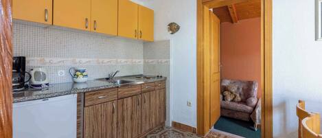 Eine kleine Küche mit Holzausstattung, einer gefliesten Rückwand und einem gemusterten Boden.
