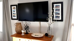 A flat-screen TV mounted on a wall above a wooden console with decorative items. - Lake house retreat (Abbeville)