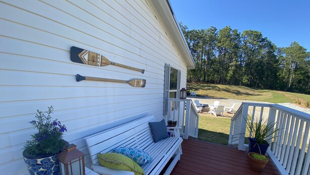 A white porch with a wooden bench, a small table with a lantern, and a potted plant. - Lake house retreat (Abbeville)
