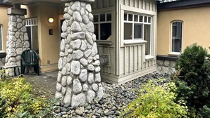 Una casa con un pilar de piedra, un porche cubierto y una ventana con marco blanco.