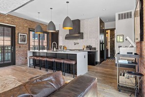 A modern kitchen with a central island, bar stools, and pendant lighting.