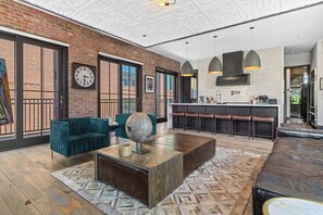 A modern interior with a brick wall, a green sofa, a coffee table, and a bar area with stools.