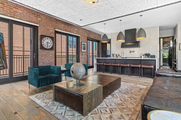 Un intérieur moderne avec un mur en briques, un canapé vert, une table basse et un coin bar avec des tabourets.