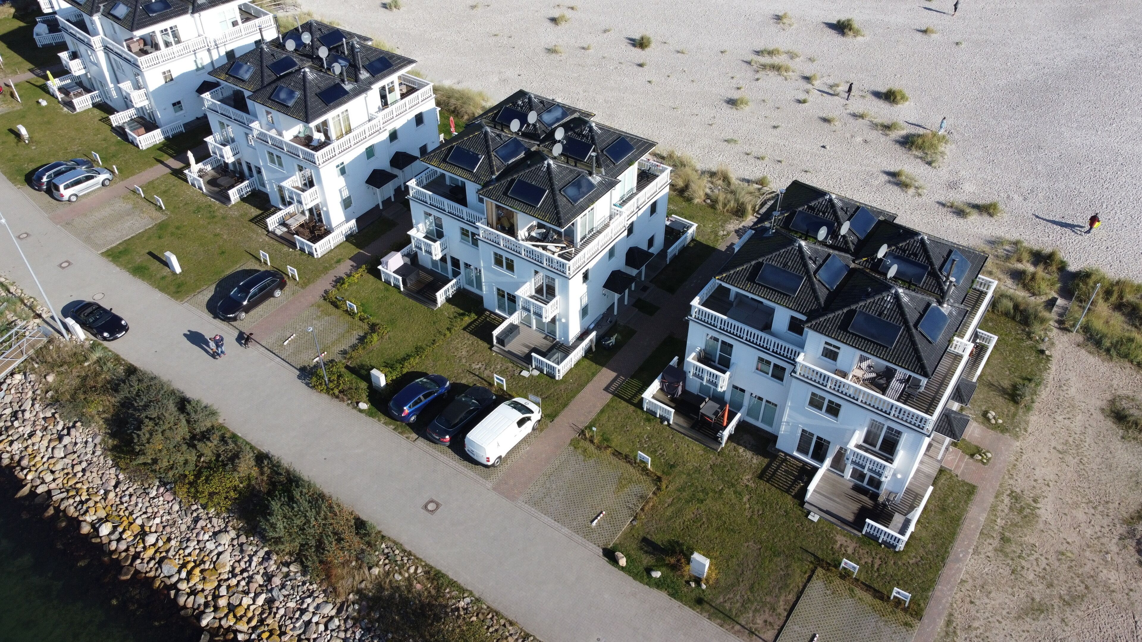A residential area with multiple two-story houses, each with a balcony and solar panels on the roof.