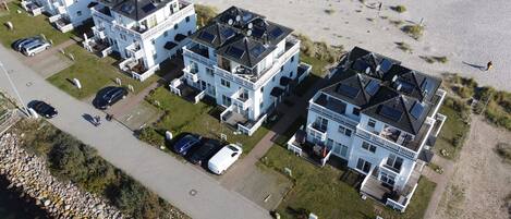 A residential area with multiple two-story houses, each with a balcony and solar panels on the roof.