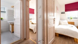 A bedroom with a bed, a nightstand, a window with a view, and a door leading to a bathroom. - Vacation home Captains Hus directly on the Baltic Sea beach (Kappeln)
