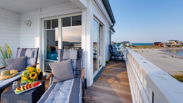 A beachfront property with a covered patio, outdoor seating, and a view of the beach and ocean. - Vacation home Captains Hus directly on the Baltic Sea beach (Kappeln)