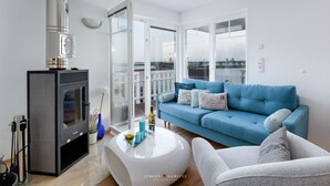 A modern living room with a fireplace, a blue sofa, and a white coffee table. - Vacation home Captains Hus directly on the Baltic Sea beach (Kappeln)