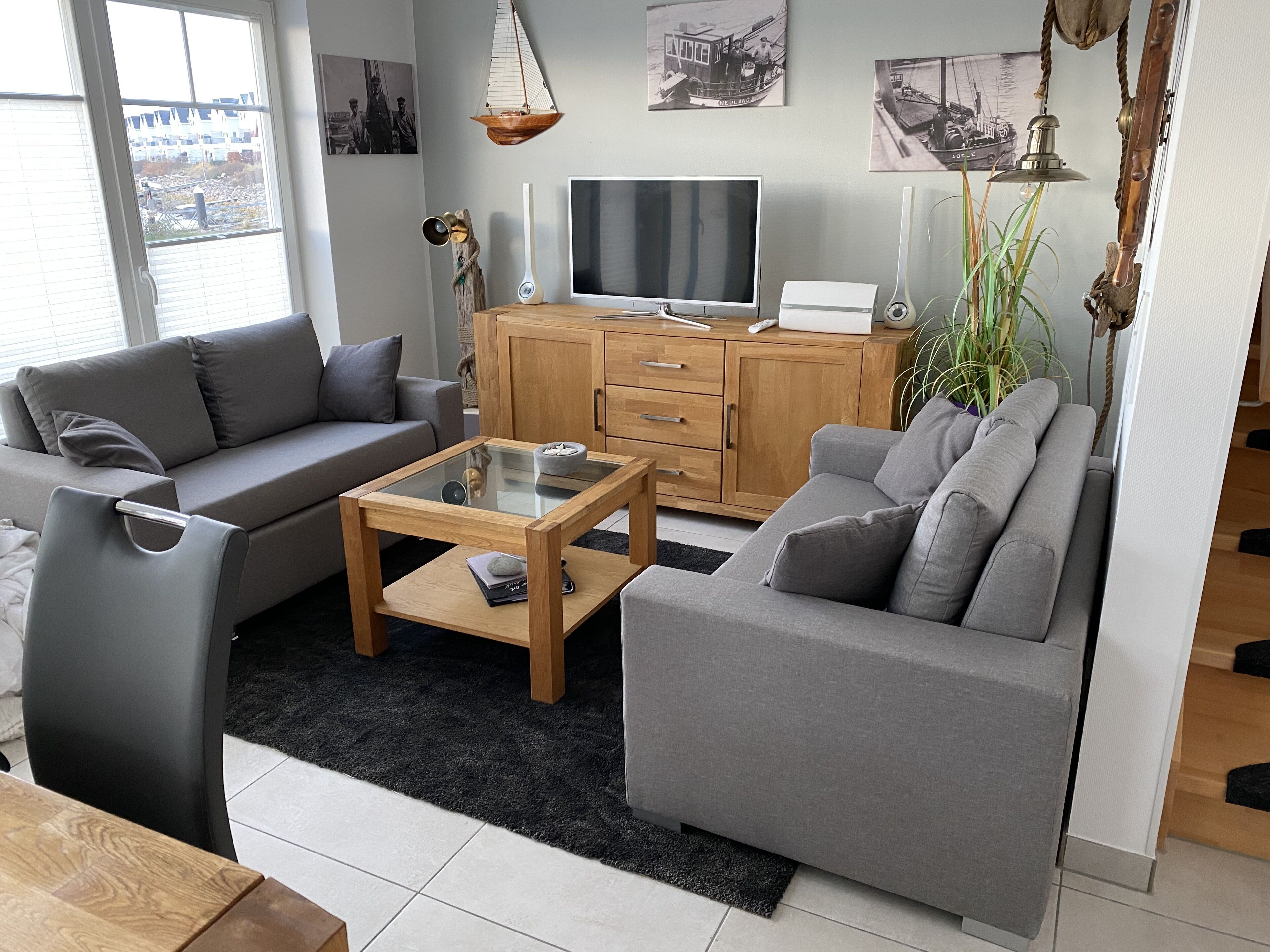 A modern living room with a grey sofa, a glass coffee table, a wooden cabinet, and a TV.