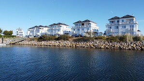 A waterfront property with multiple white buildings, a rocky shoreline, and a bridge leading to the buildings. - Vacation home Captains Hus directly on the Baltic Sea beach (Kappeln)