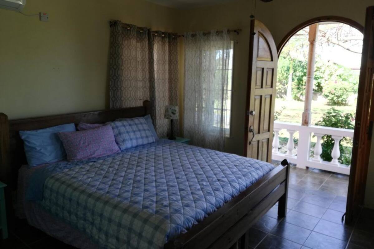 A bedroom with a bed, curtains, a window, and a balcony.
