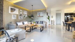 A modern living room with a sofa, coffee table, and dining area. There are framed pictures on the wall and a potted plant. - Villa Sunny Day with Pool (Labin)