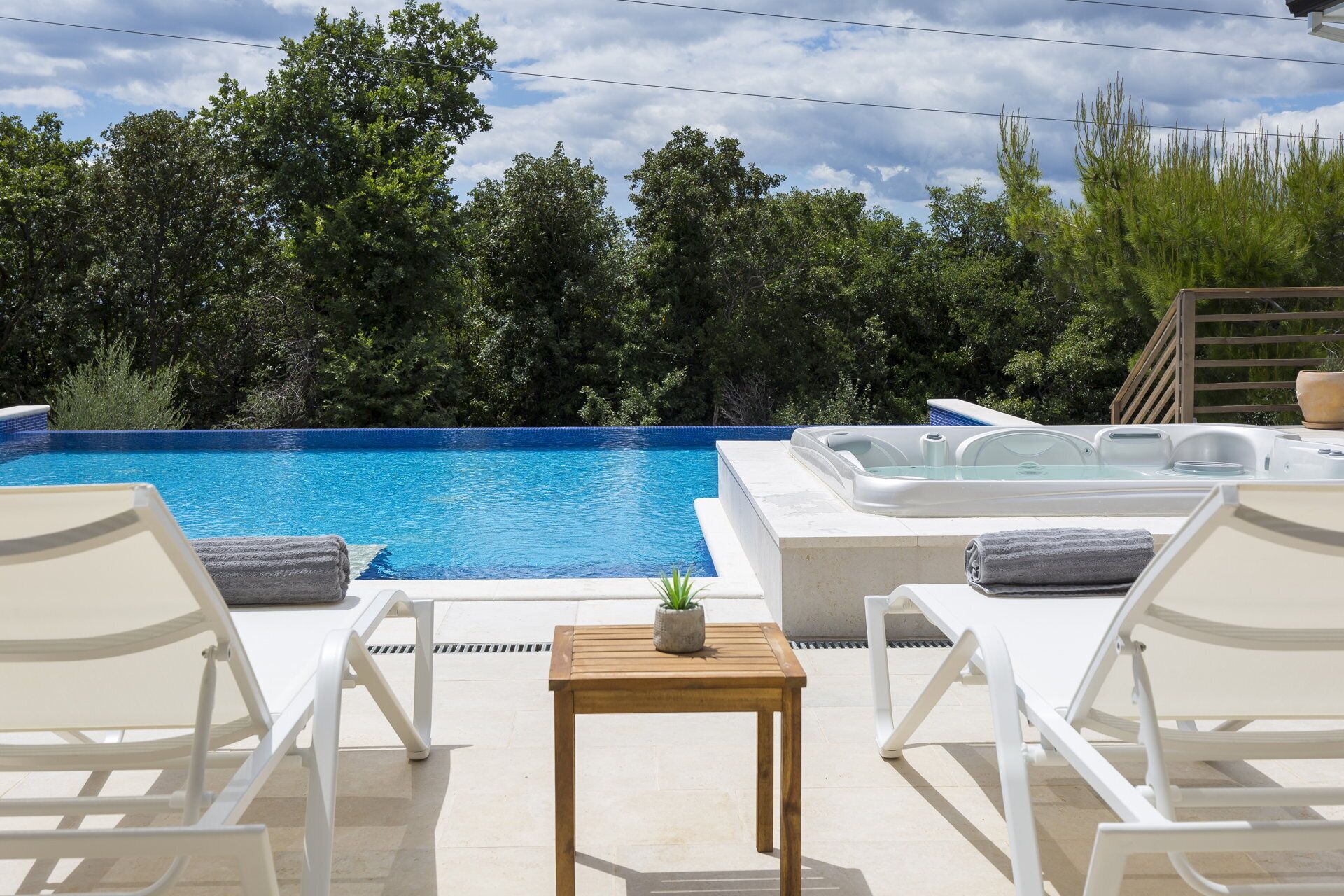 A pool area with lounge chairs and a hot tub.