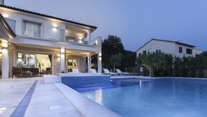 A modern house with a swimming pool, outdoor seating, and a well-lit patio area. - Villa Sunny Day with Pool (Labin)