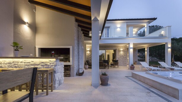 A modern outdoor living area with a stone fireplace, seating, and a pool. - Villa Sunny Day with Pool (Labin)