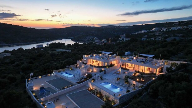 Una villa moderna con varios niveles, piscina al aire libre y vistas del paisaje circundante.