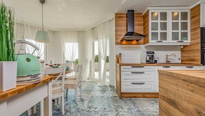 A modern kitchen with white cabinets, a wooden countertop, and a built-in stove.