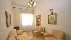 A living room with a sofa, armchair, and a small table with a vase.