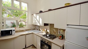A kitchen with white cabinets, a microwave, a sink, a stove, and a refrigerator.