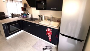 Una cocina moderna con armarios negros, un refrigerador de acero inoxidable, un microondas y un horno empotrado.