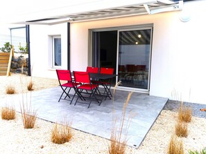 An outdoor patio with a table and chairs, a sliding glass door, and a gravel ground.