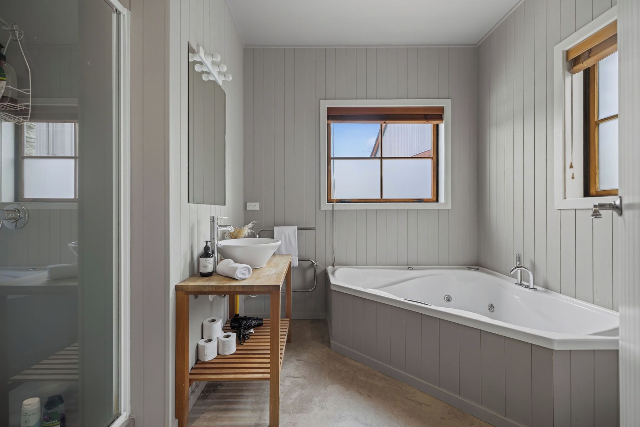 A modern bathroom with a freestanding bathtub, a vanity with a mirror, and a window providing natural light.