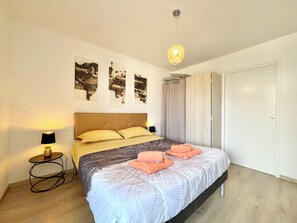 Ein Schlafzimmer mit Bett, Nachttisch, Lampe und Wandbildern.