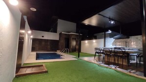 Ett modernt utomhusområde med en swimmingpool, en bar och en matplats.