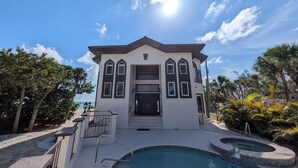 Une maison à deux étages avec une piscine, entourée d’une végétation tropicale.
