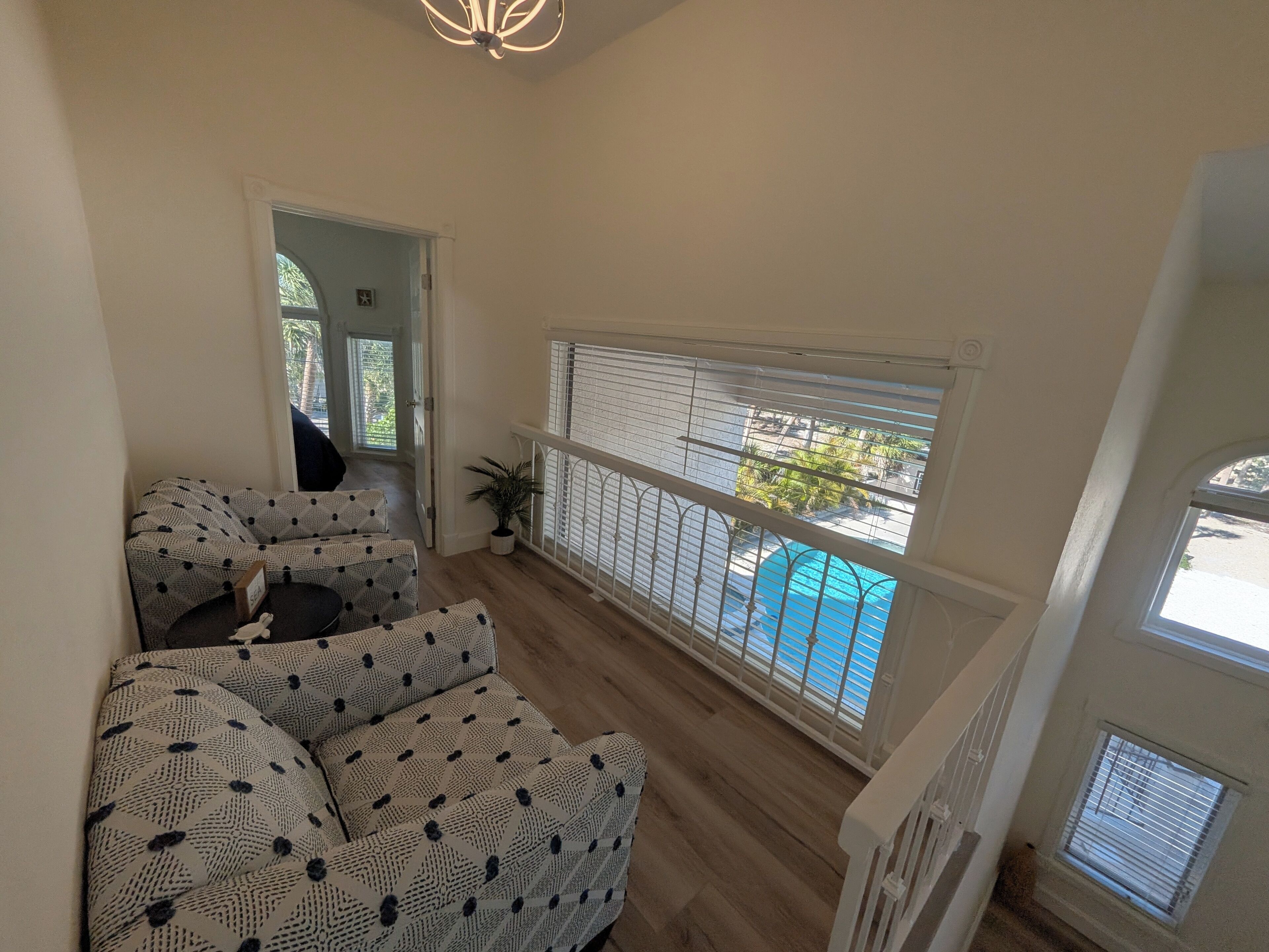 A spacious living area with a view of a swimming pool, a staircase, and a potted plant.