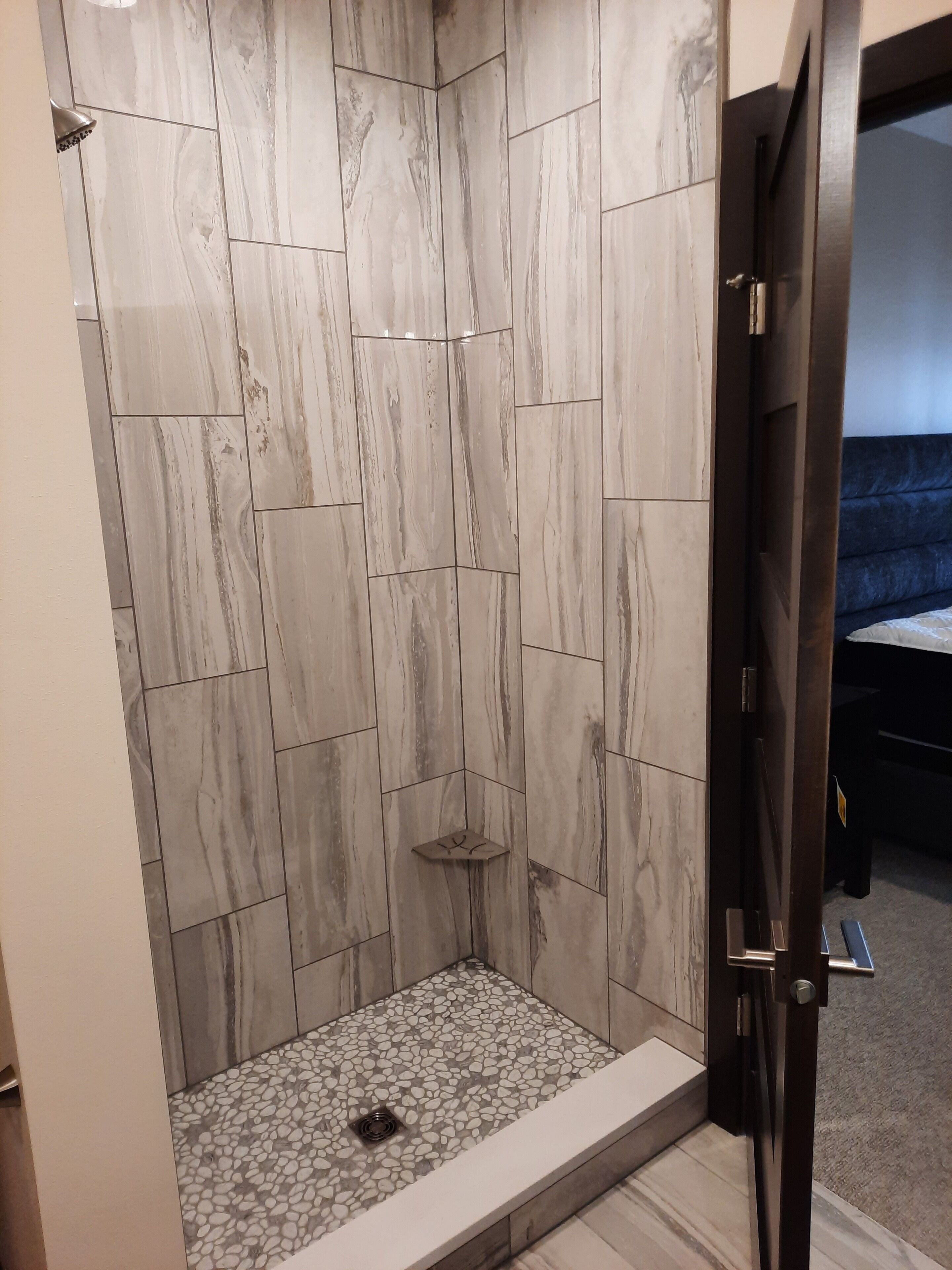 A walk-in shower with a tiled floor and a showerhead.