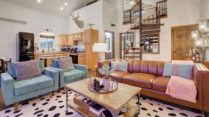 A spacious living room with a sofa, armchairs, a coffee table, and a staircase leading to an upper level. - Sky Cabin • Mountain Sauna • Hot Tub • Yellowstone (Emigrant)