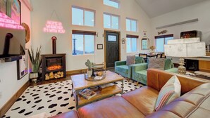 A spacious living room with a fireplace, multiple sofas, a coffee table, and a large window with a view. - Sky Cabin • Mountain Sauna • Hot Tub • Yellowstone (Emigrant)