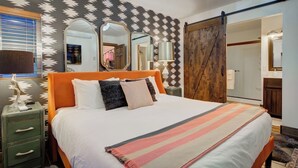 A bedroom with a large bed, a dresser, a mirror, and a sliding door leading to a bathroom. - Sky Cabin • Mountain Sauna • Hot Tub • Yellowstone (Emigrant)