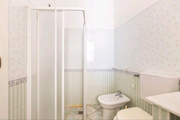 A bathroom with a shower, sink, and toilet.