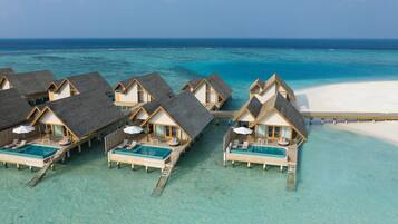 Overwater bungalows with infinity pools, wooden walkways, and a clear view of the ocean.