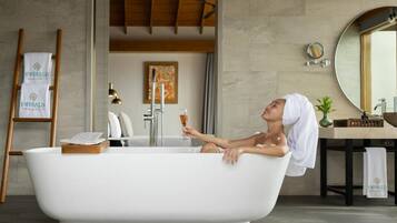 A modern bathroom with a freestanding bathtub, a wooden ladder, a towel rack, and a mirror.