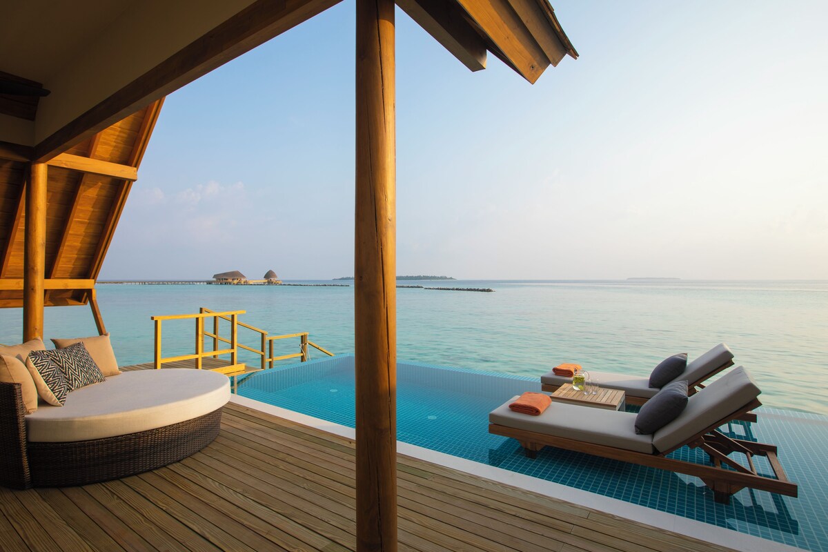 An infinity pool with wooden deck seating and a view of the ocean.