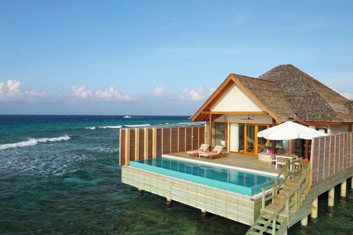 An overwater villa with a private pool, wooden deck, and ocean view.