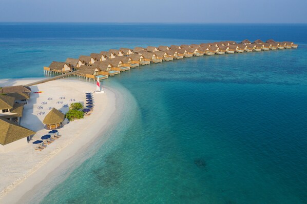 An overwater resort with thatched-roof bungalows connected by walkways, a sandy beach, and clear turquoise waters. - Emerald Faarufushi Resort & Spa (Faarufushi)