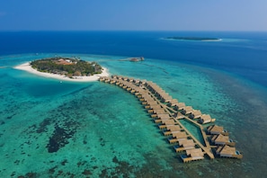 An aerial view of an overwater resort with a long row of overwater bungalows connected by a walkway, surrounded by clear turquoise waters and a small island with a beach. - Emerald Faarufushi Resort & Spa (Faarufushi)