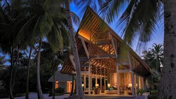 A beachfront resort with a wooden structure, palm trees, and a sandy beach.