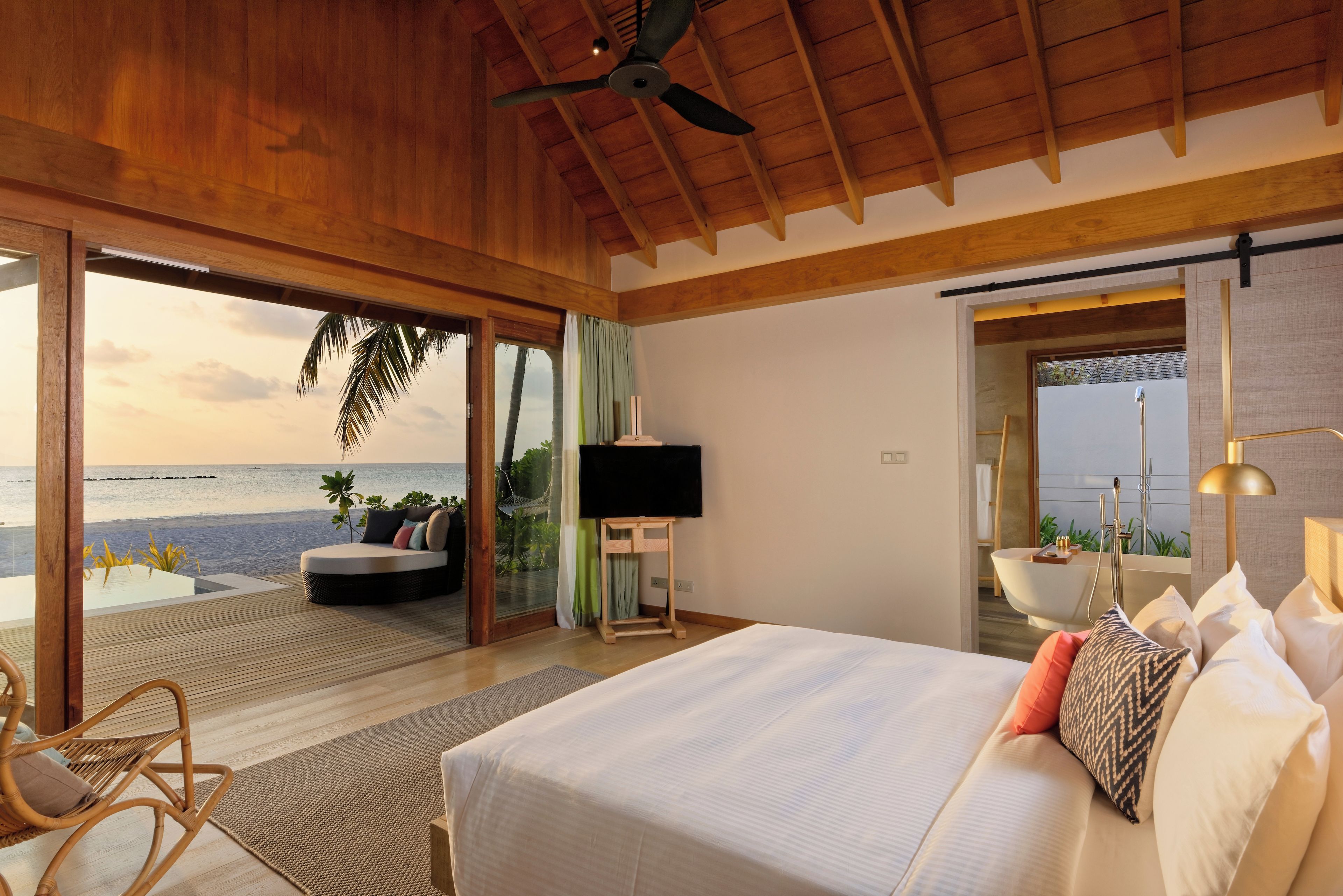 A bedroom with a large bed, a TV, and a view of the beach.
