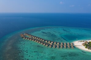 An aerial view of overwater bungalows aligned in a U-shape, connected by walkways, with clear turquoise waters and a distant shoreline. - Emerald Faarufushi Resort & Spa (Faarufushi)